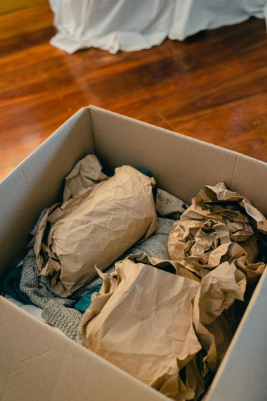 A cardboard box filled with clothes wrapped in brown paper.