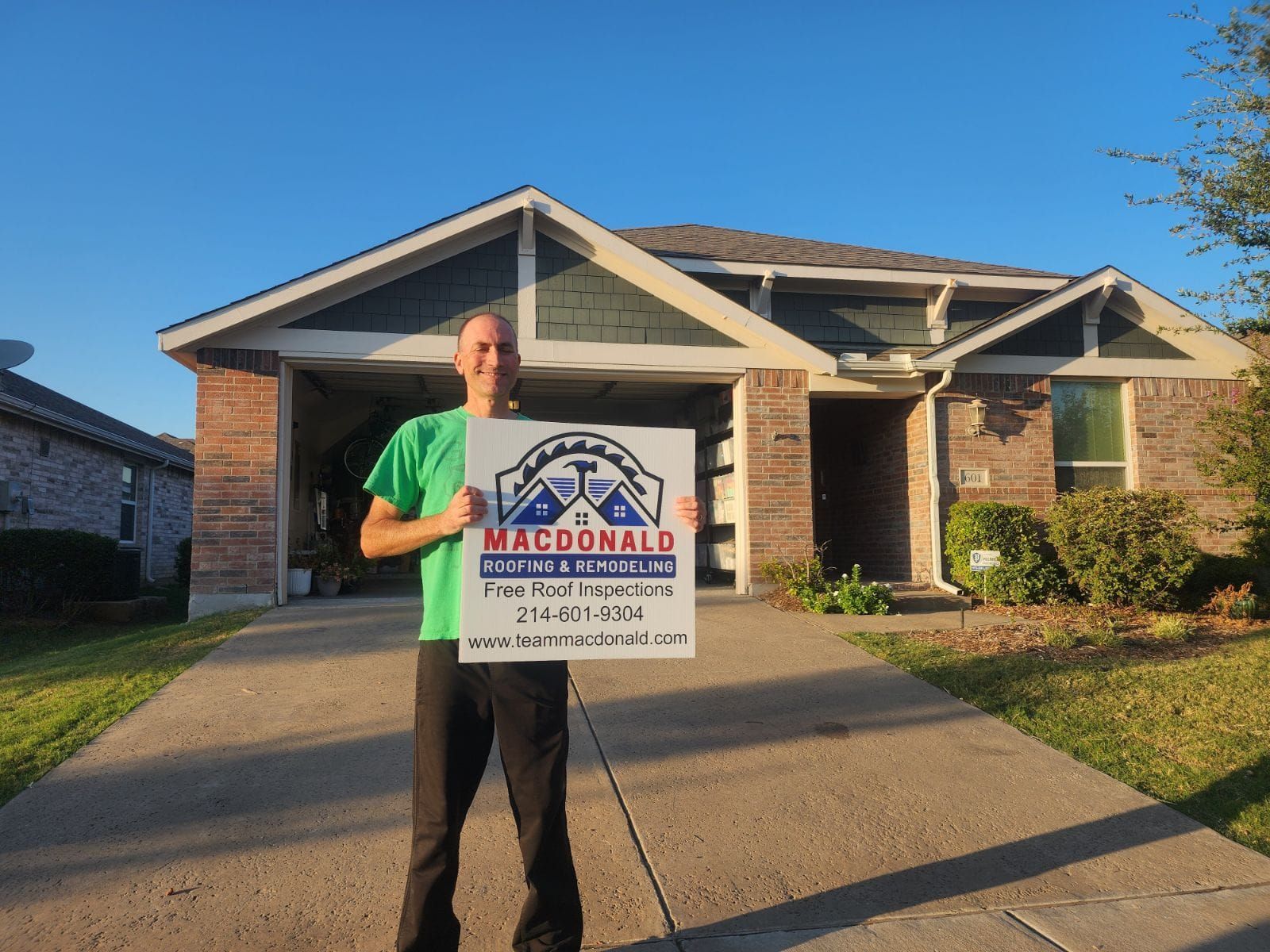 A man is holding a macdonald sign in front of a house