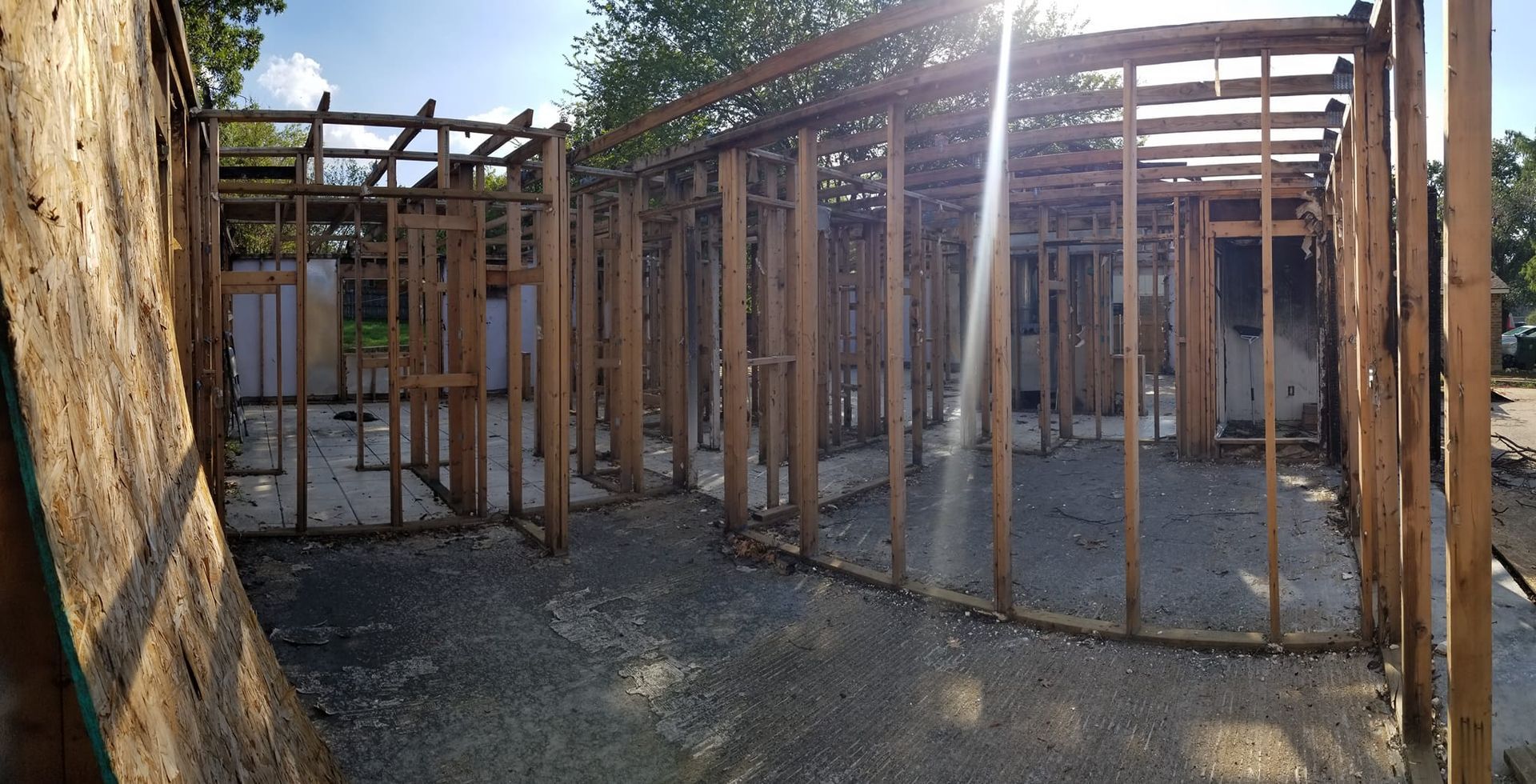 The sun is shining through the wooden frames of a house under construction.