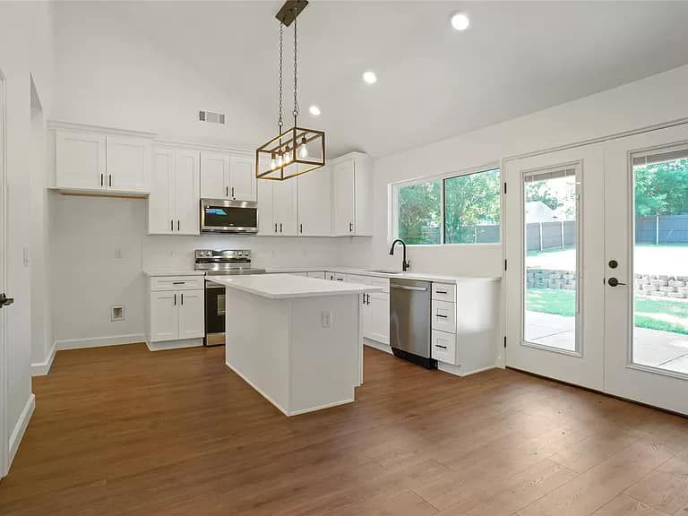 A kitchen with white cabinets , stainless steel appliances , and a large island.