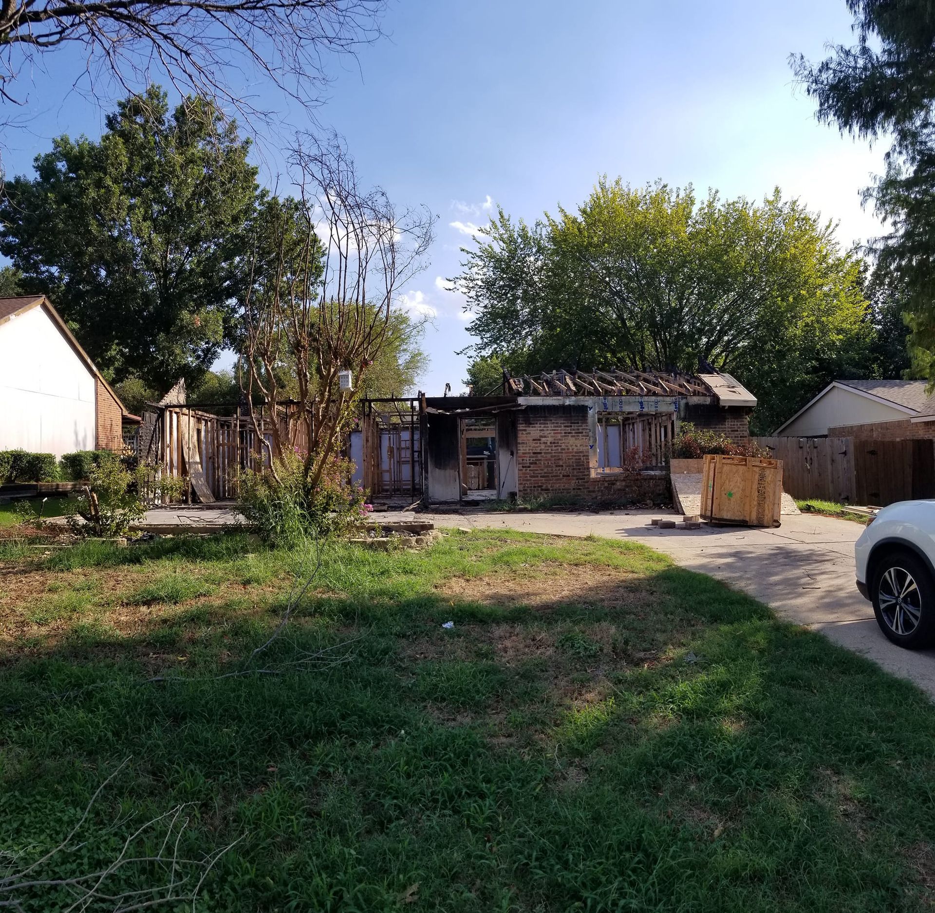 A white car is parked in front of a brick house