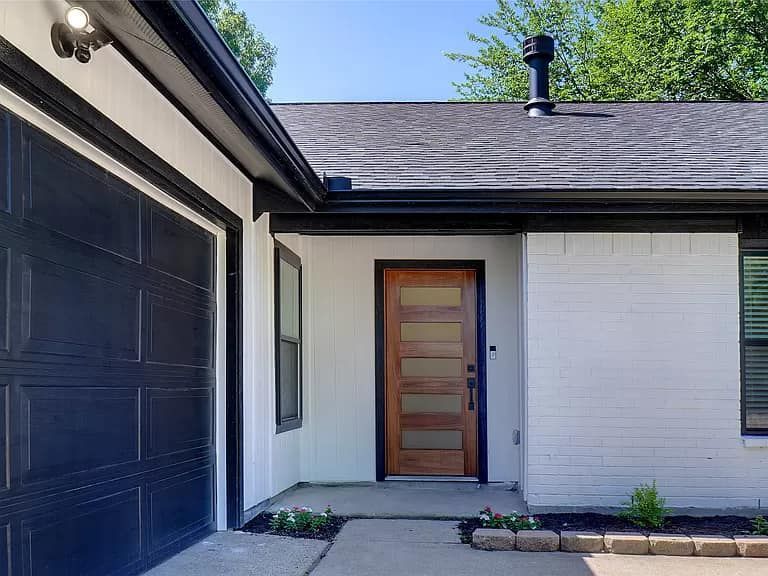 A white house with a black garage door and a wooden door.