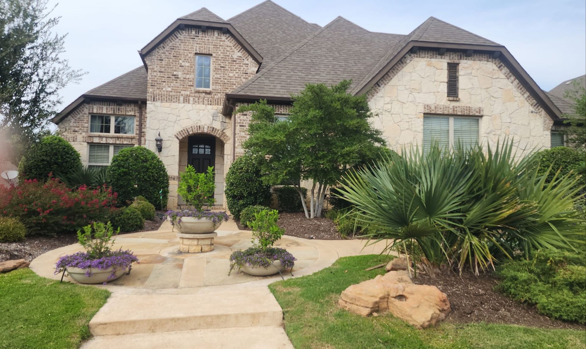 A large brick house with a lush green lawn and trees in front of it.