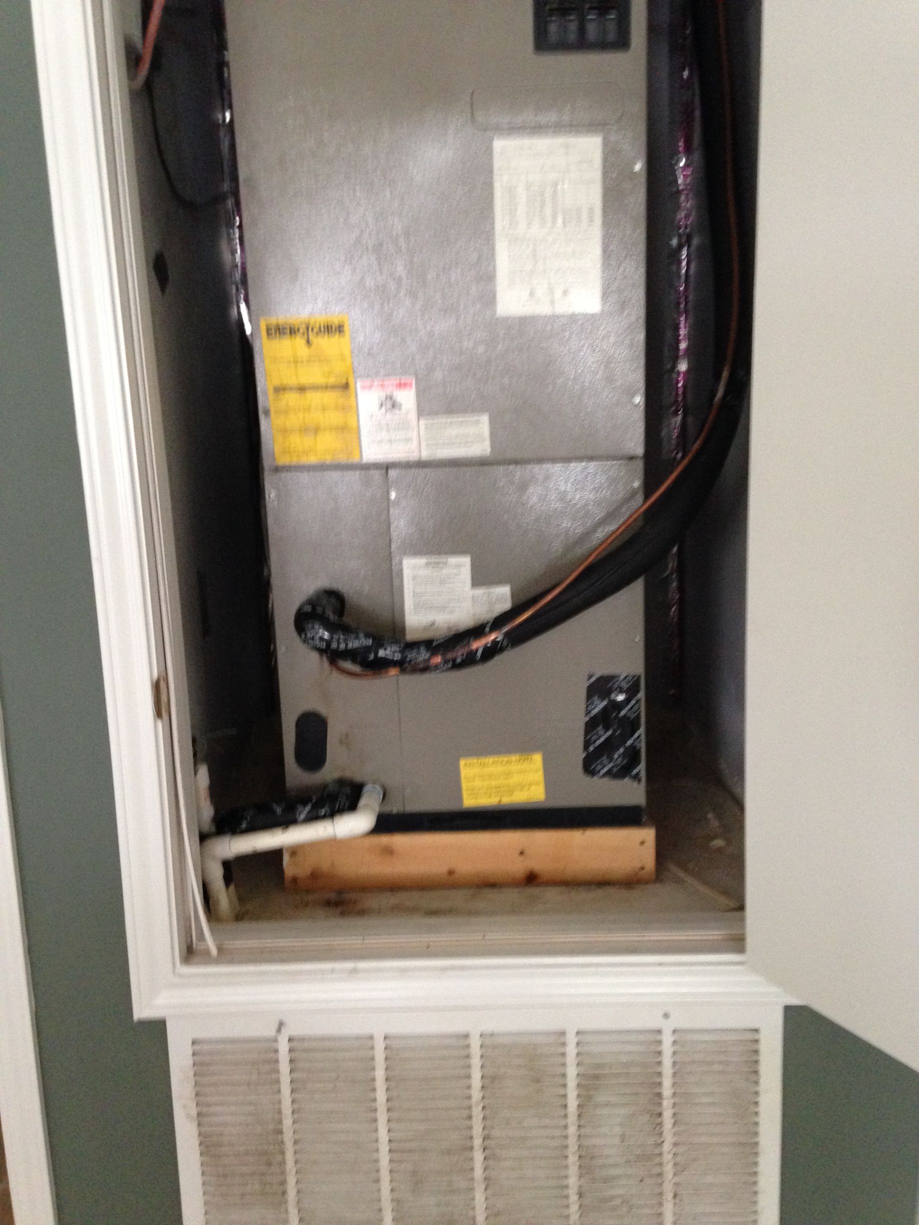 An air conditioner is sitting in a cabinet with the door open