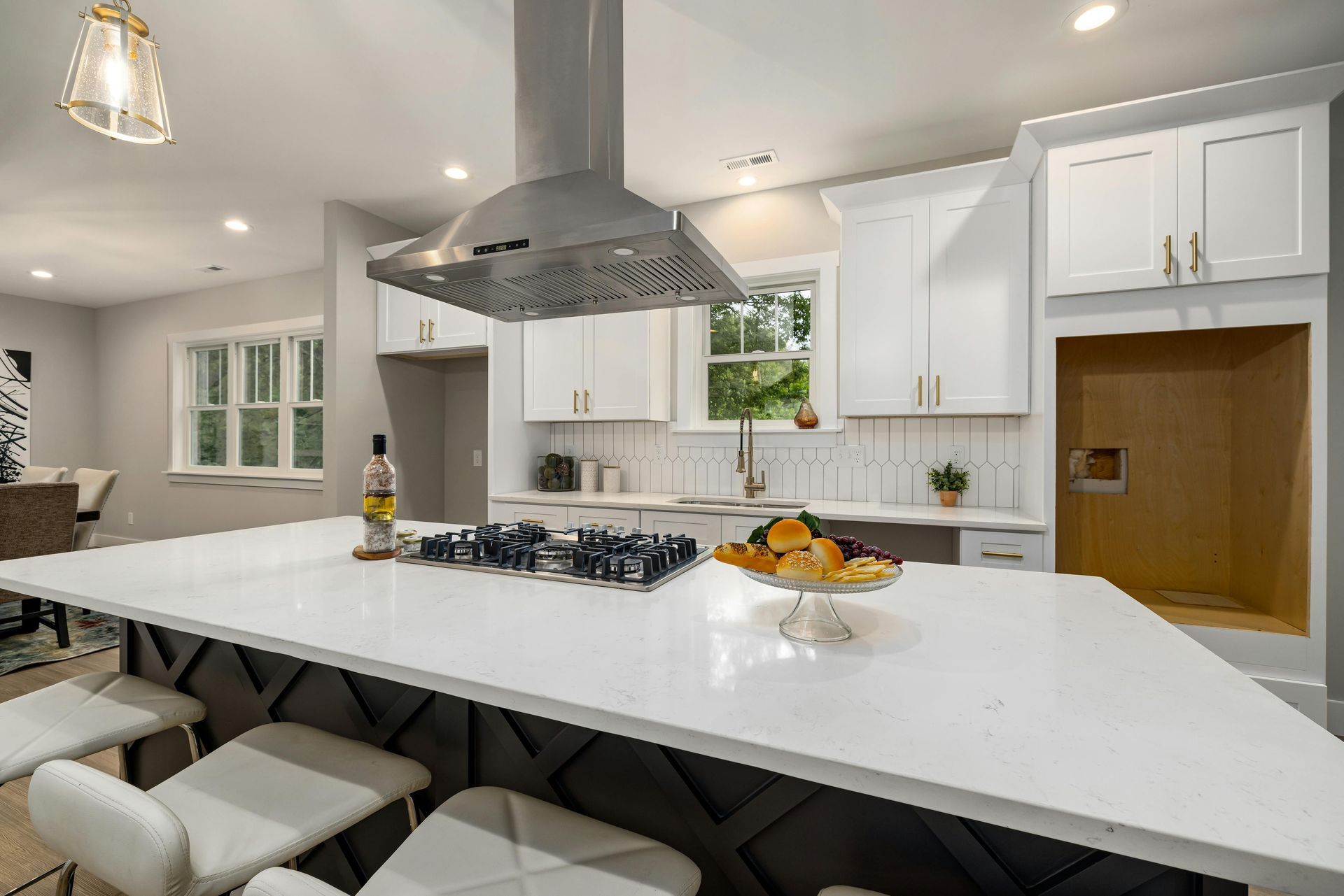 A kitchen with white cabinets and a large island with a stove top oven.