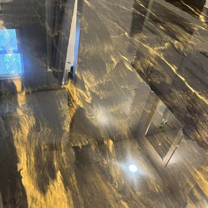 A black and gold epoxy floor in a room with a window.