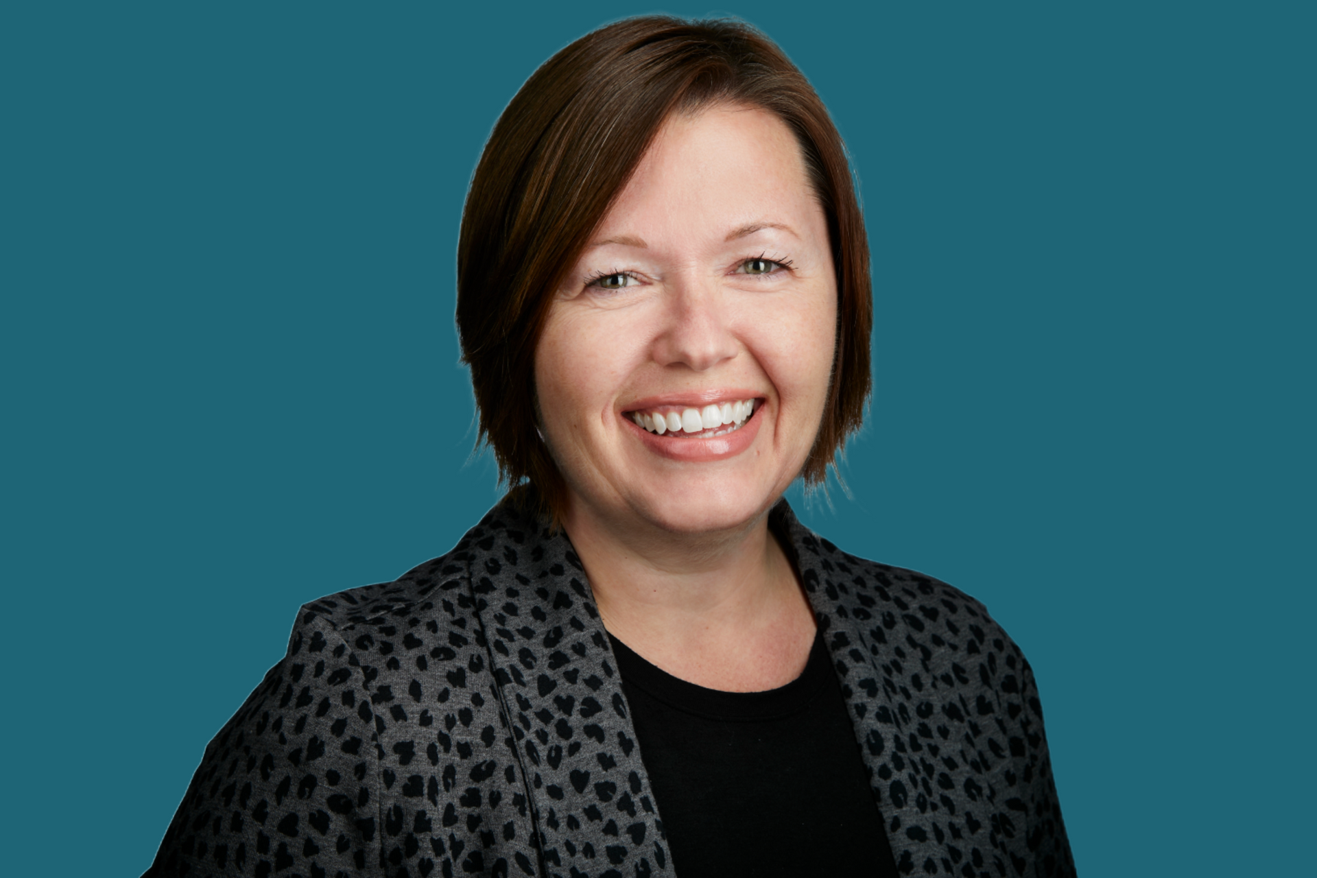 A woman in a leopard print jacket is smiling for the camera.
