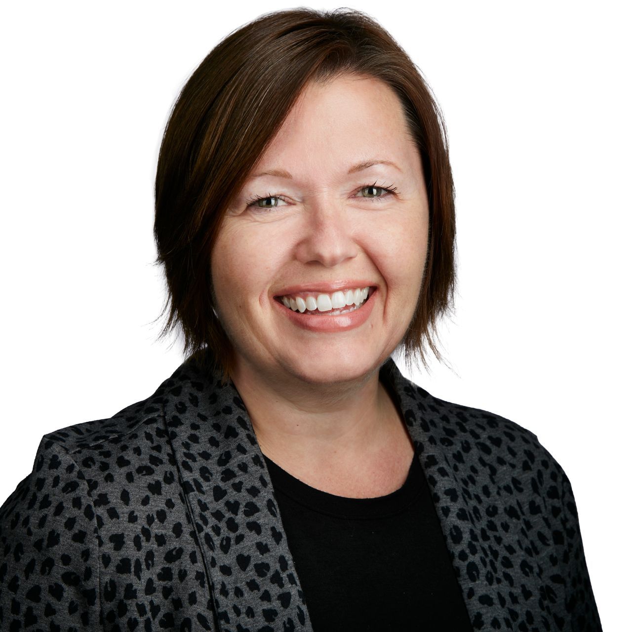 A woman wearing a leopard print jacket is smiling for the camera