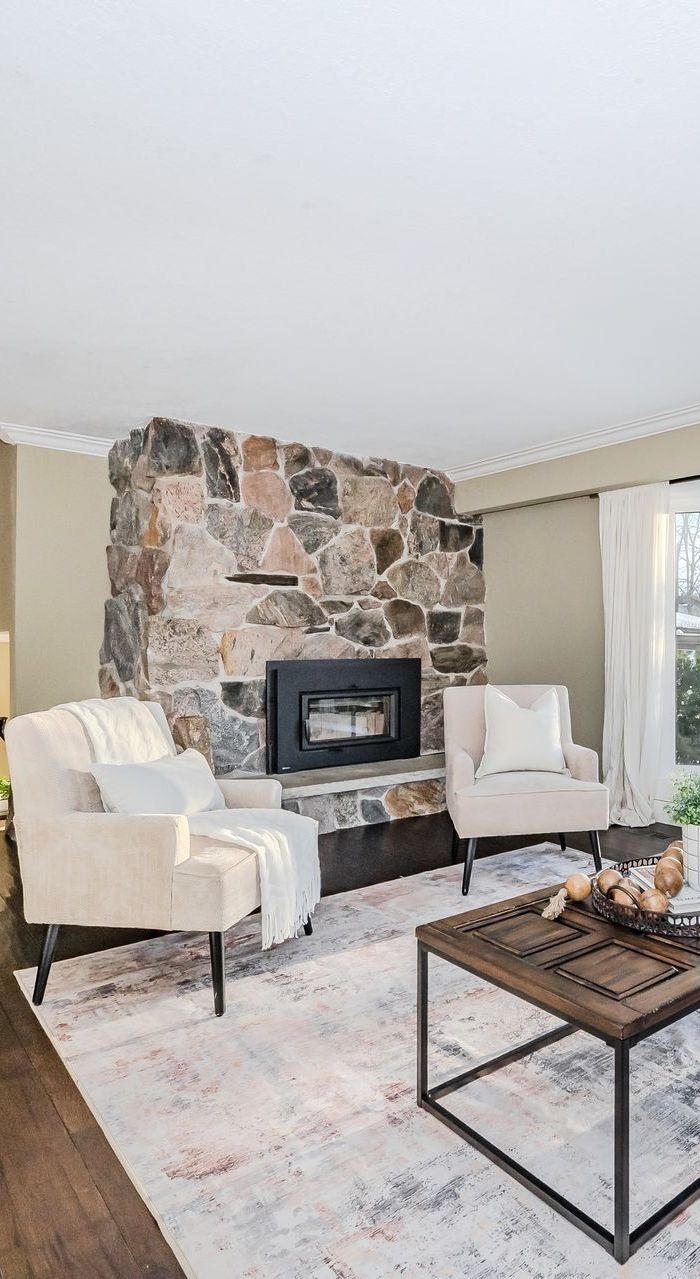 A living room with a fireplace , coffee table , and mirror.