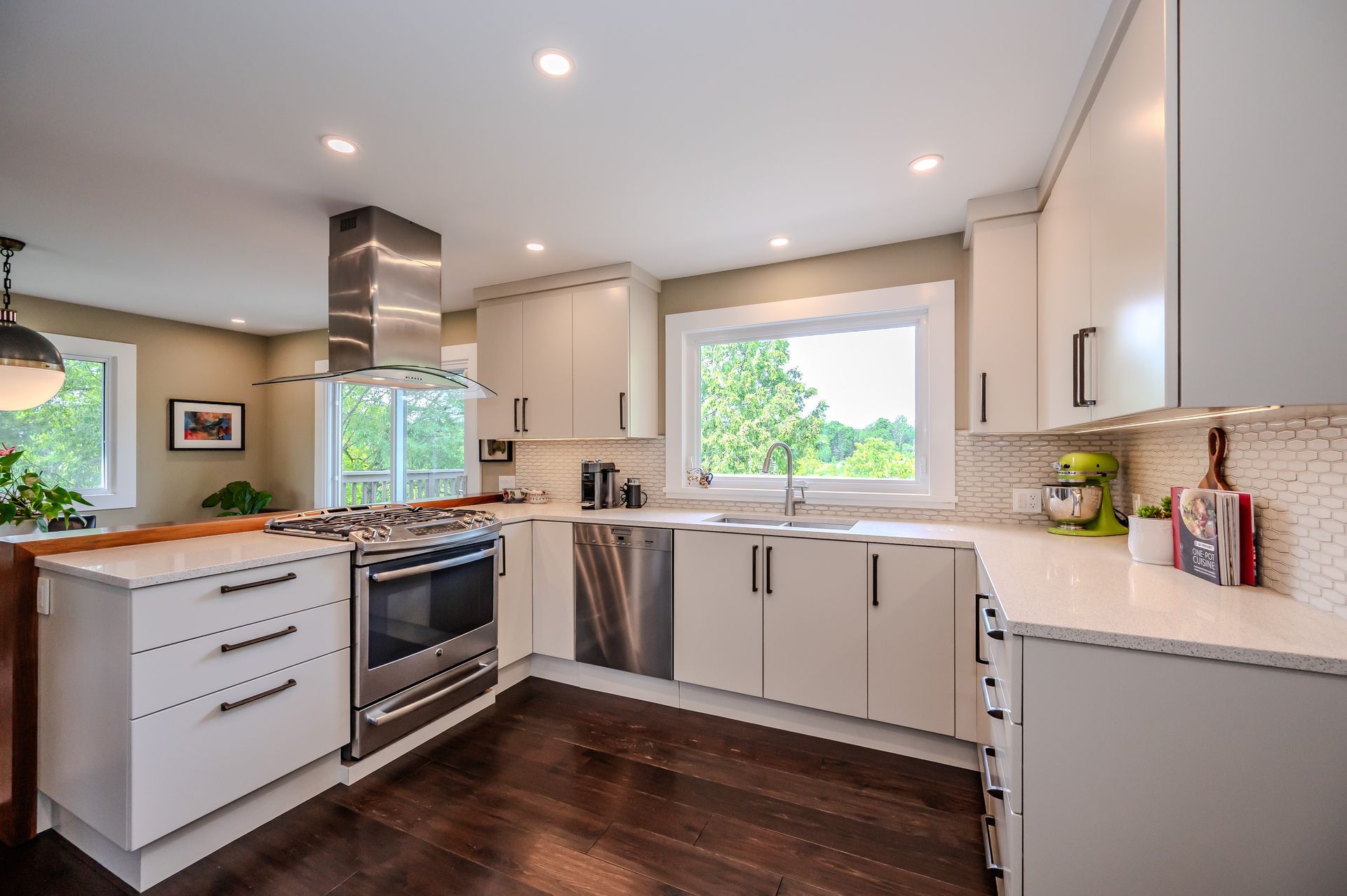 A kitchen with a large island and white chairs.