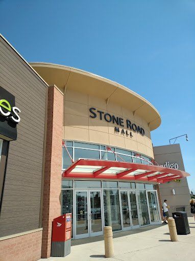 The stone road mall has a red awning over the entrance