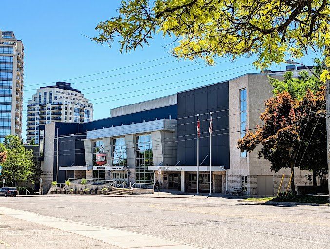 A large building with a lot of windows is surrounded by trees and power lines.