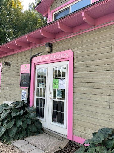 A pink building with a white door and a sign on it.