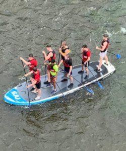 A group of people are on a paddle board in the water