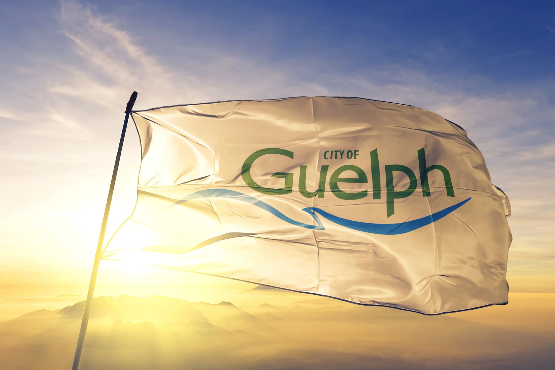 A flag with the word Guelph on it is waving in the wind.