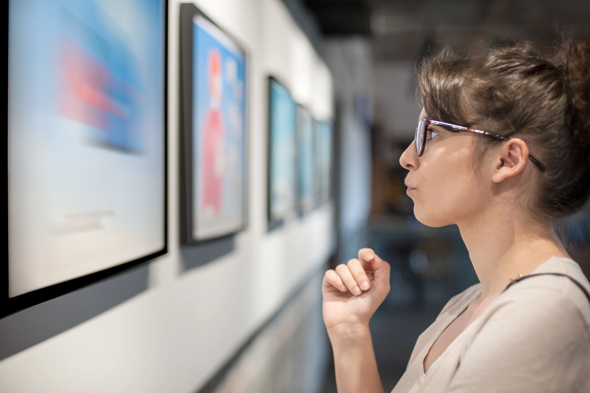 A woman is looking at a painting in an art gallery.