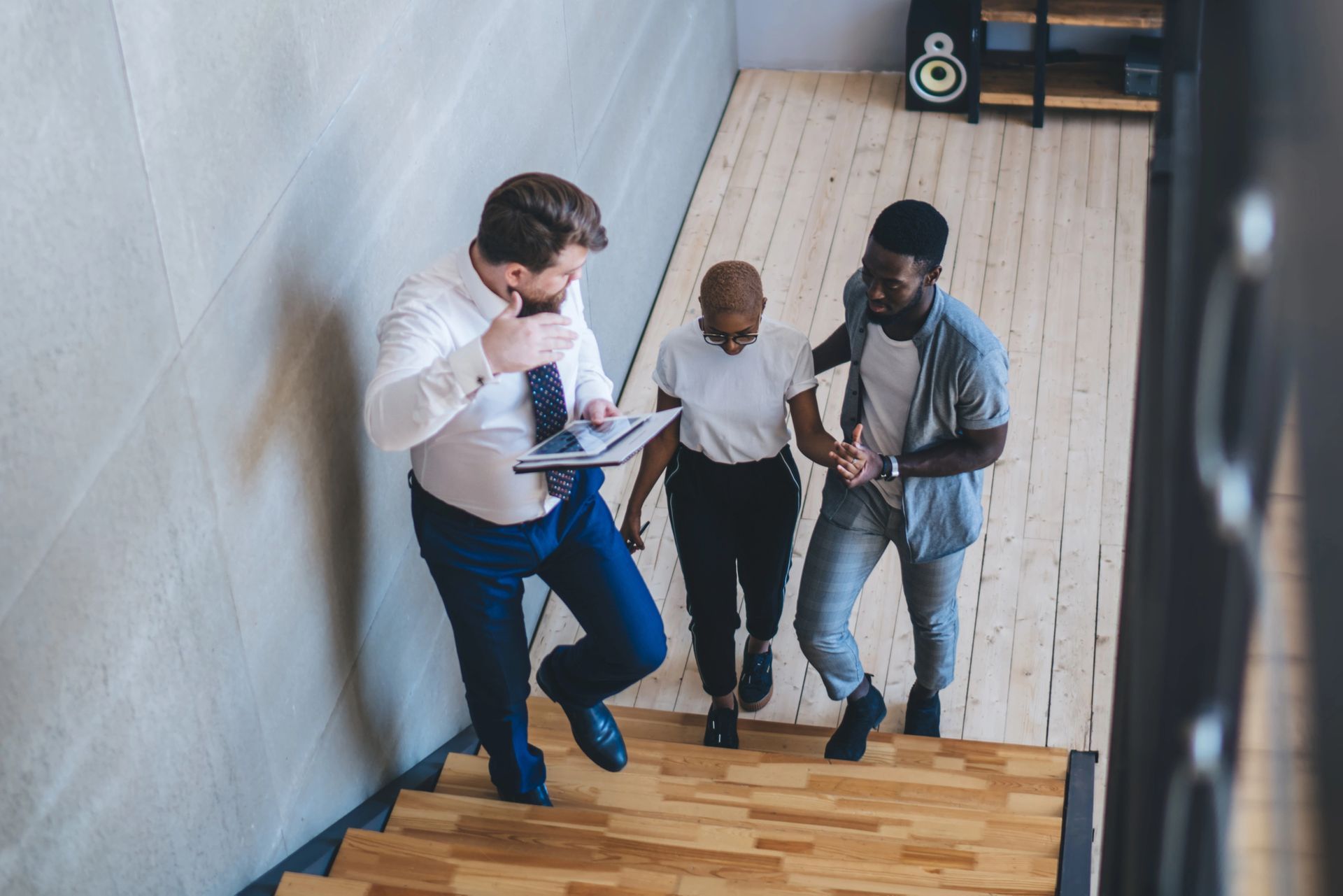 A realtor is guiding two people up some stairs.