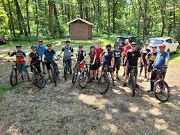 A group of people are standing next to each other on bicycles in the woods.