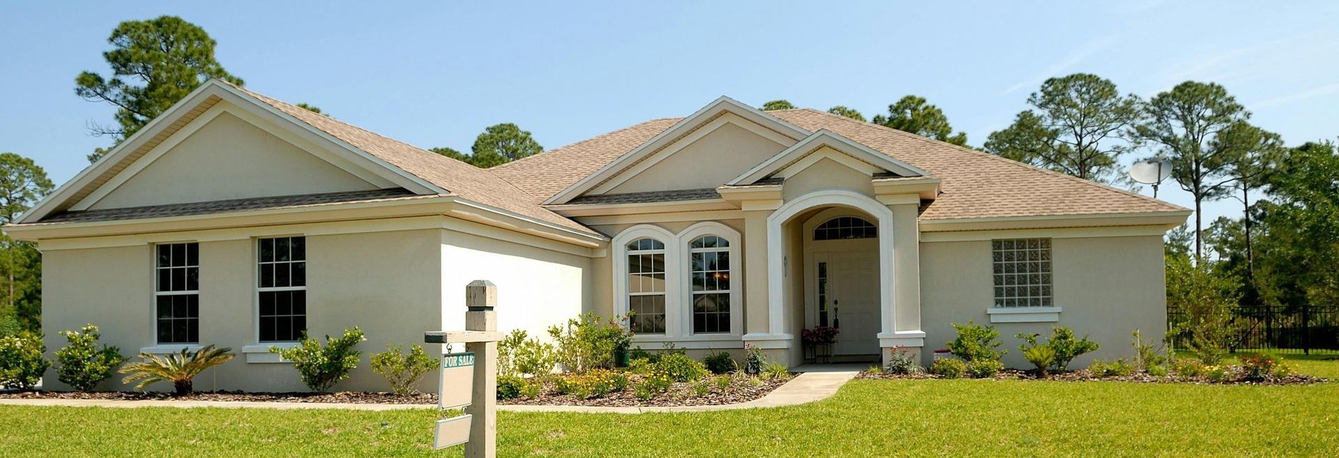 A white house with a brown roof is sitting in the middle of a lush green field.