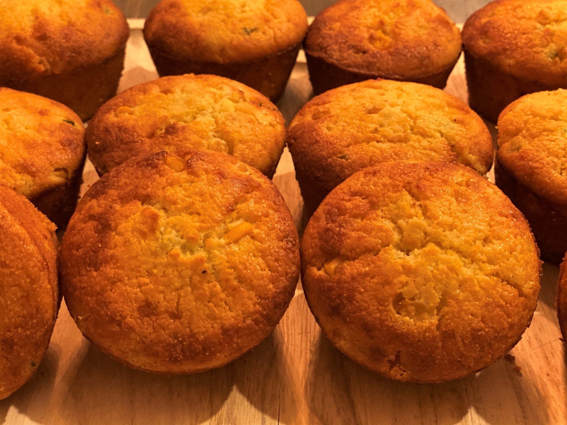 A bunch of muffins are sitting on a wooden table.