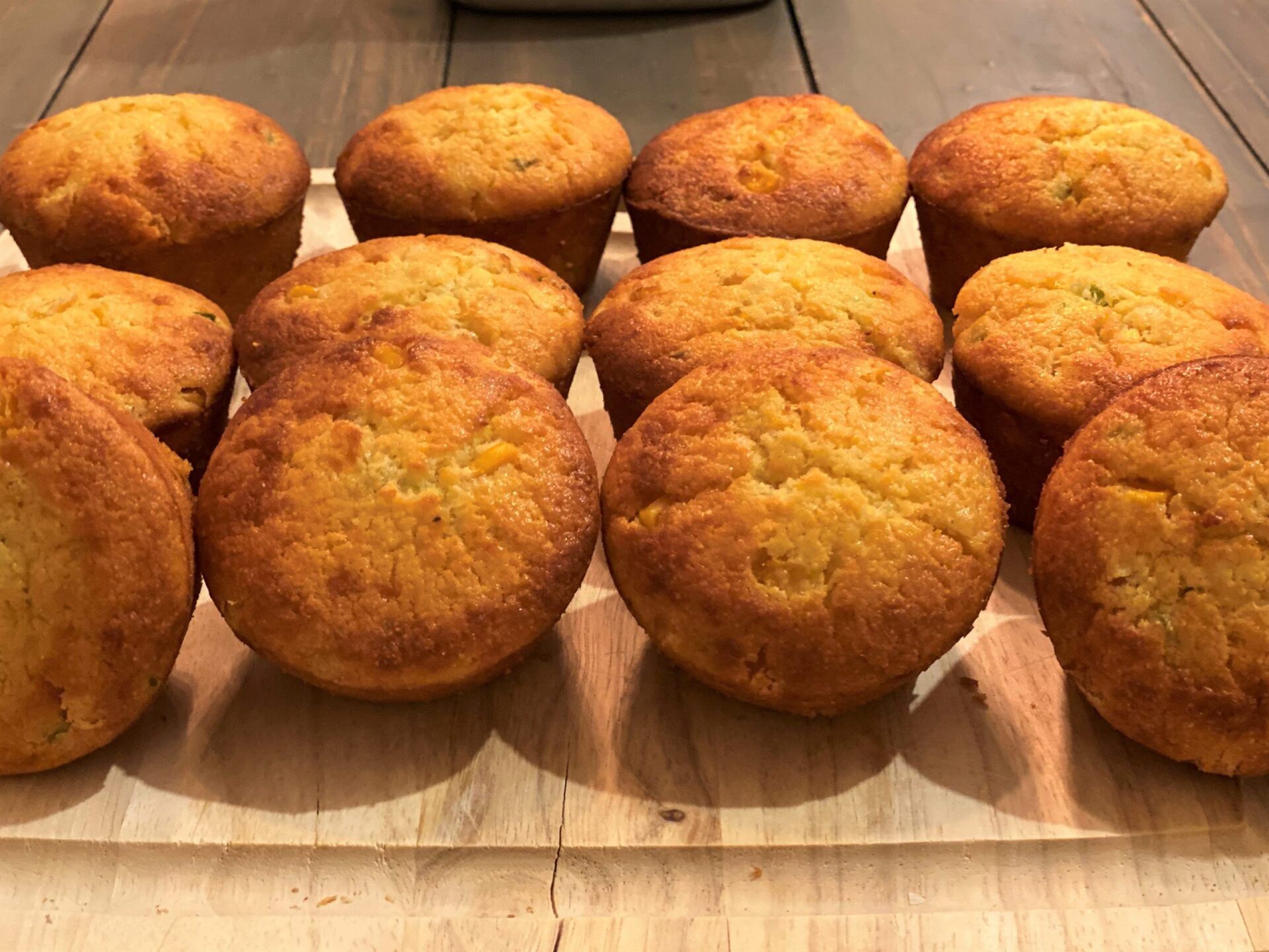 A bunch of muffins are sitting on a wooden table.