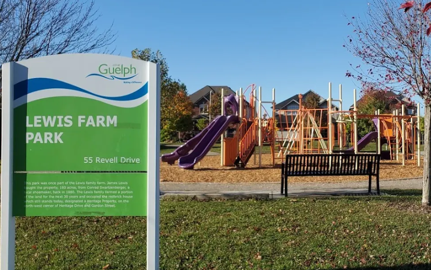 A sign for lewis farm park with a playground in the background.