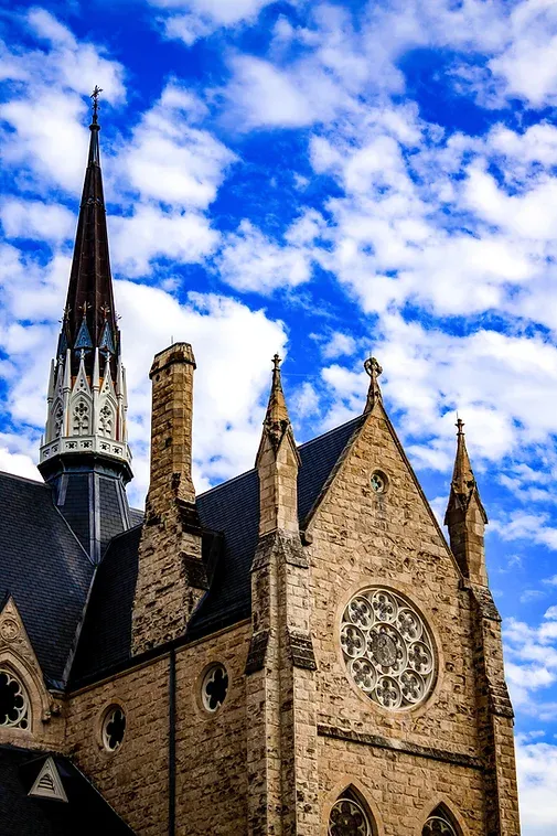A church with a steeple against a blue sky with clouds