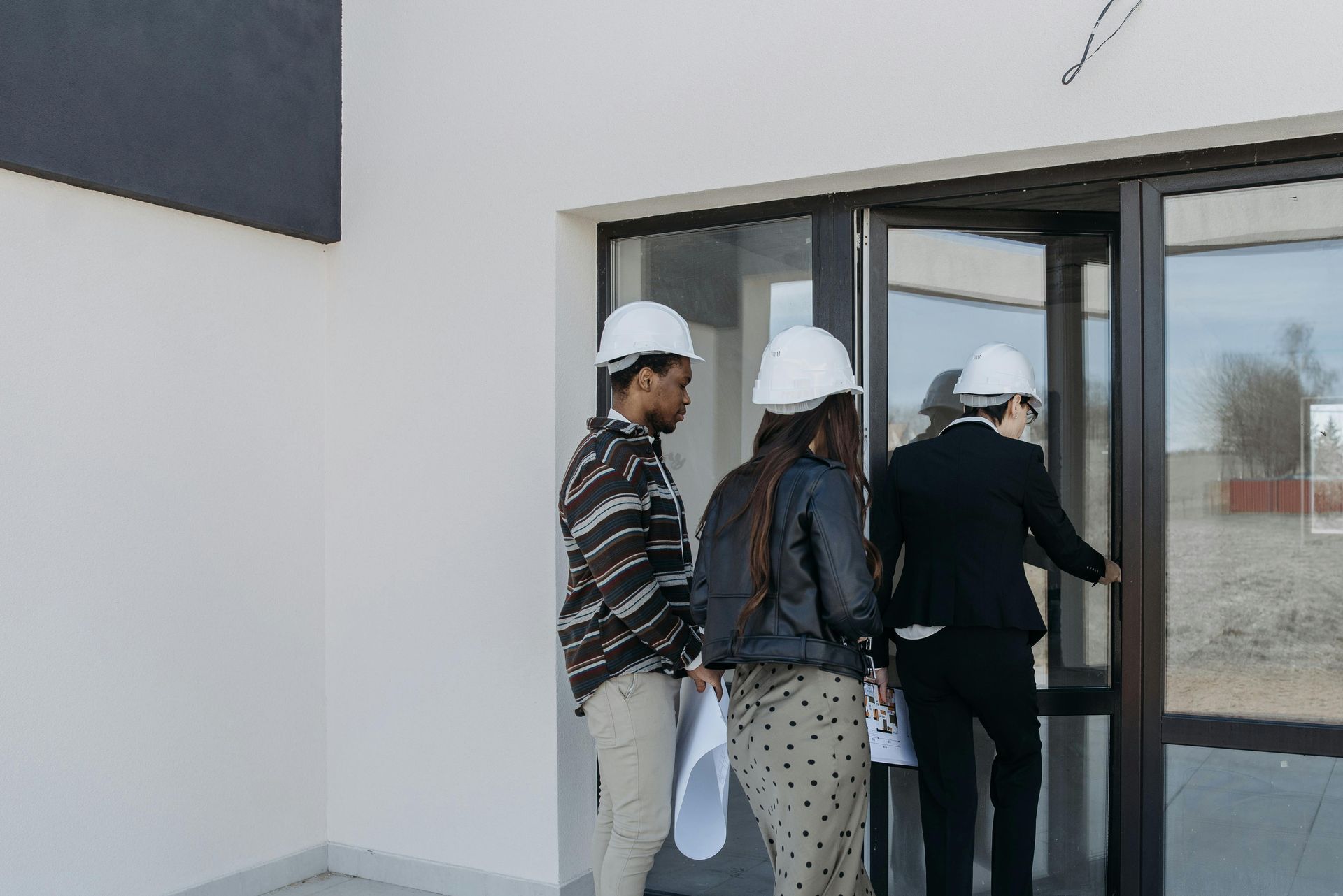 A group of people wearing hard hats are walking out of a building.