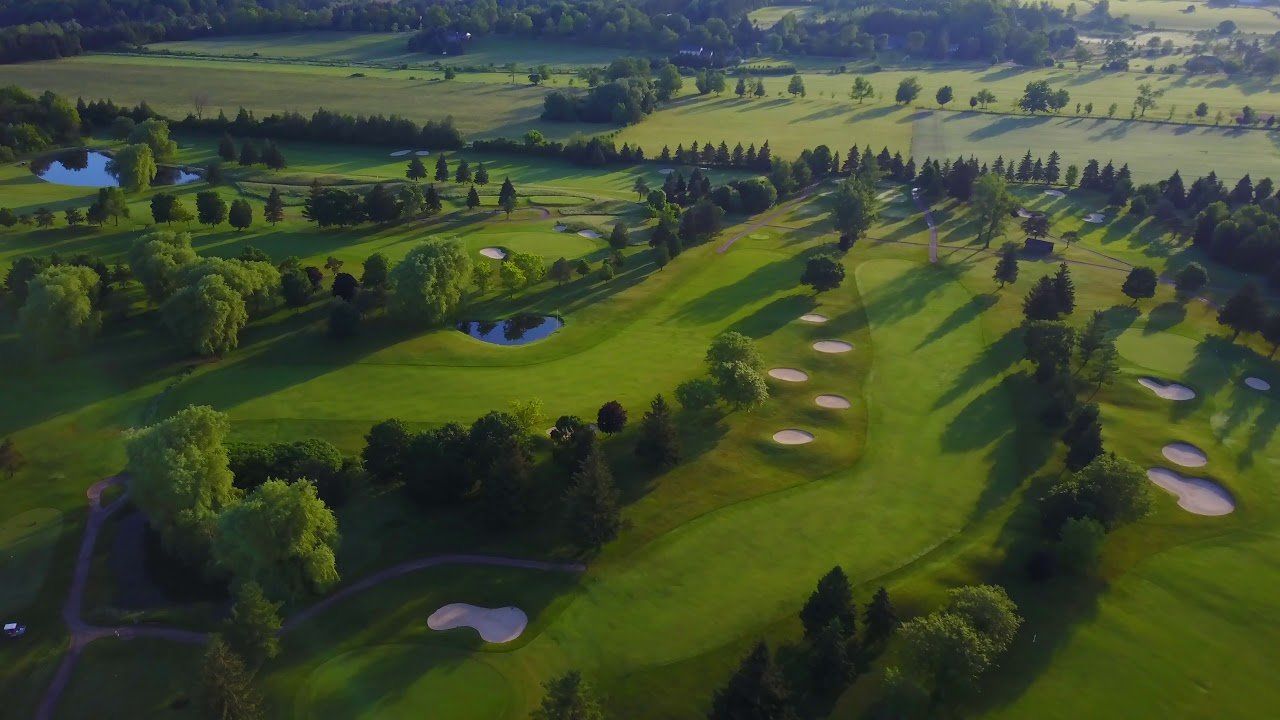 An aerial view of a golf course surrounded by trees and fields.