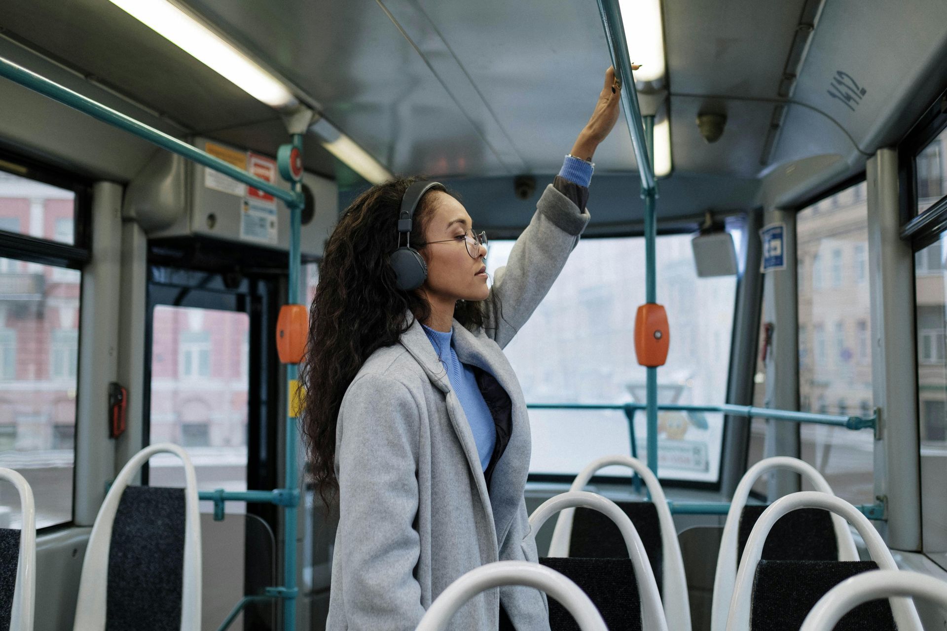 A woman wearing headphones is riding a bus.