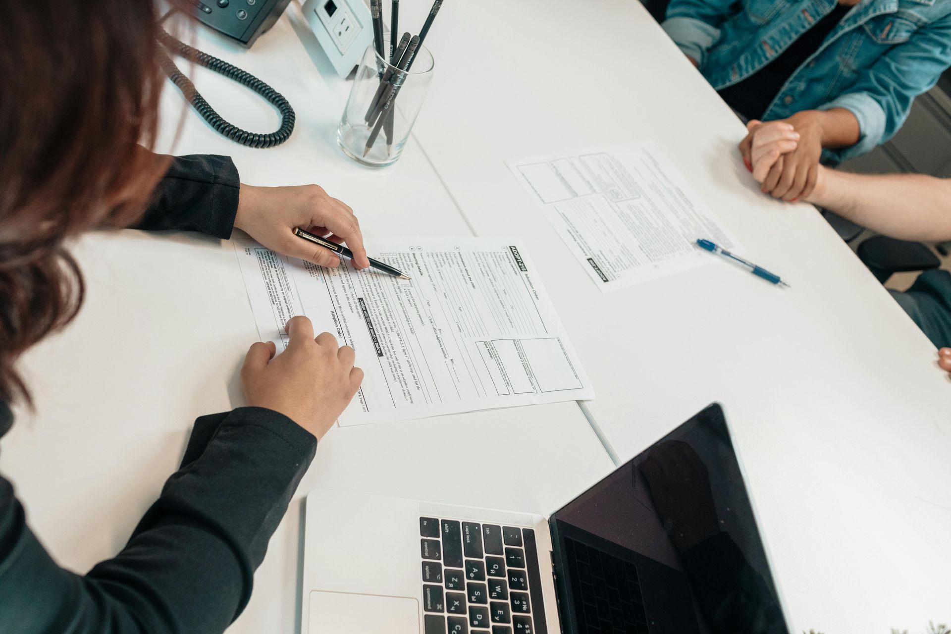 A real estate agent is sitting at a table going over offer paperwork with clients.