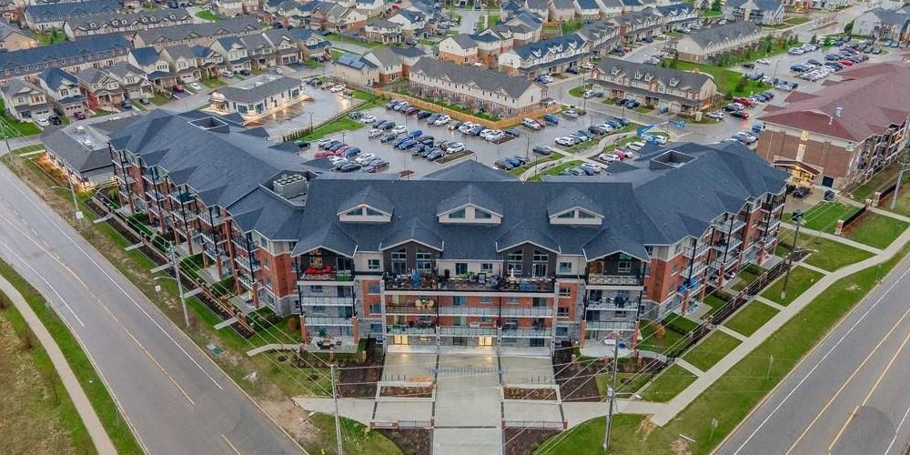 Aerial view of a residential area with many houses, roads, and trees under a cloudy sky.