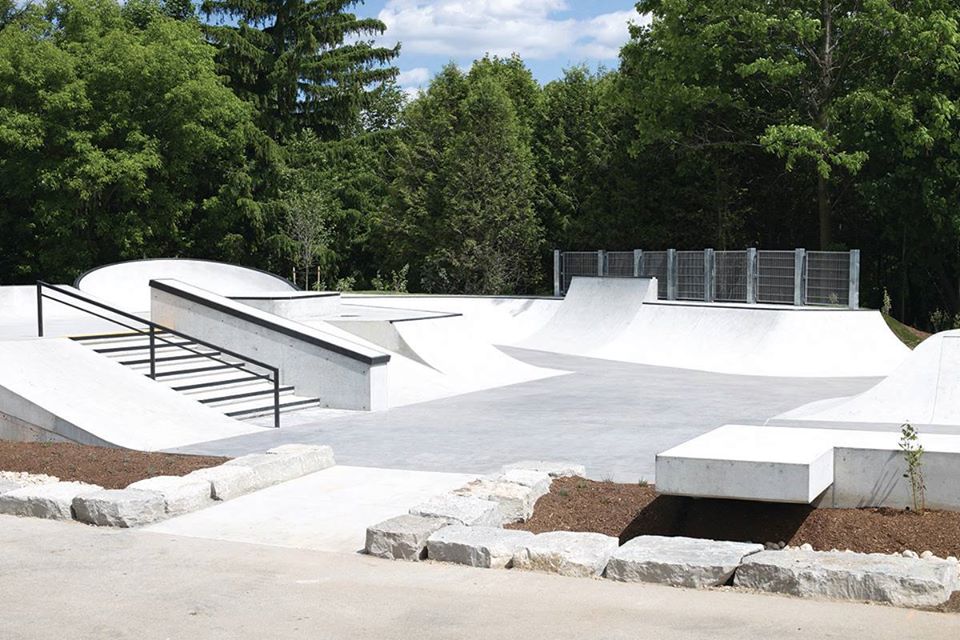 A skate park is surrounded by trees on a sunny day