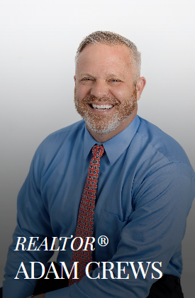 Adam Crews, Realtor, smiling, wearing a blue shirt and patterned tie.