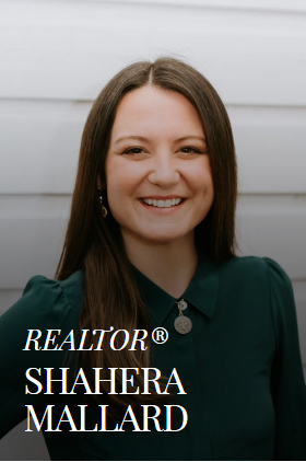 Shahera Mallard, realtor, smiling in front of a white wood-paneled wall. Wearing a dark green shirt and realtor pin.
