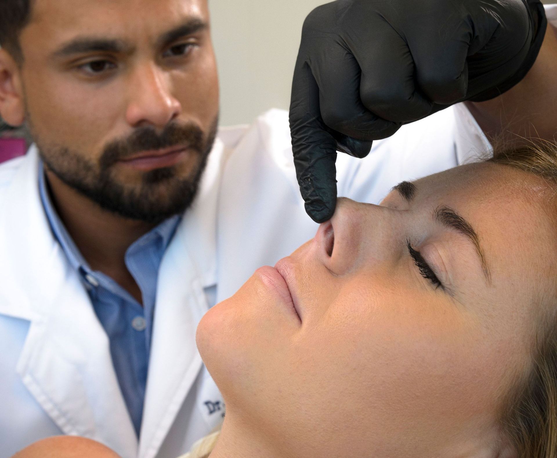 A man is giving a woman a botox injection in her face.