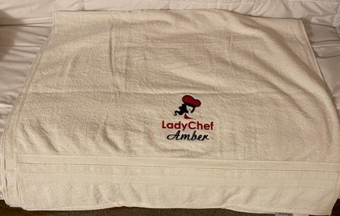 White towel featuring an embroidered red chef hat logo and the text 