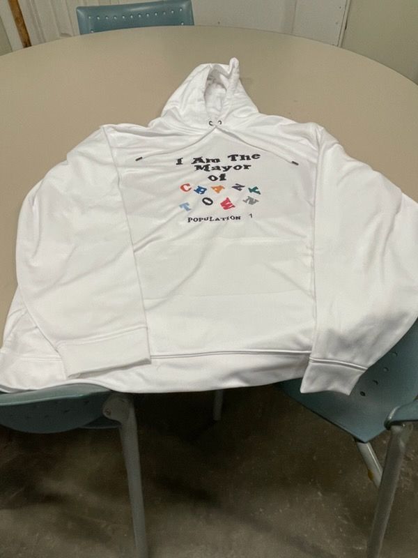 A white hooded sweatshirt draped over a chair, featuring the text 