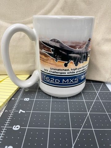 A white mug featuring a fighter jet graphic, the text 