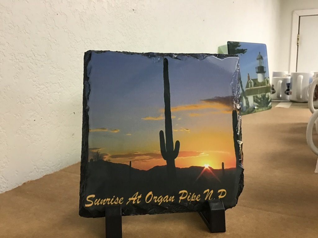A rectangular stone plaque on a stand featuring a sunrise silhouette of a saguaro cactus, labeled 