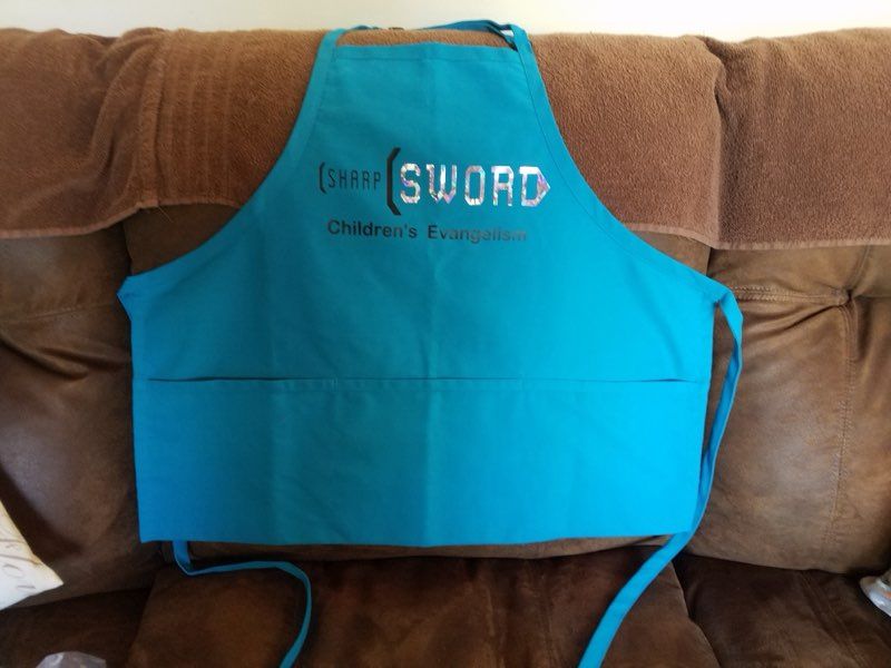 A bright blue apron with two front pockets, labeled 