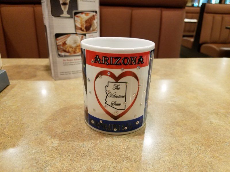 A souvenir mug on a table reads 