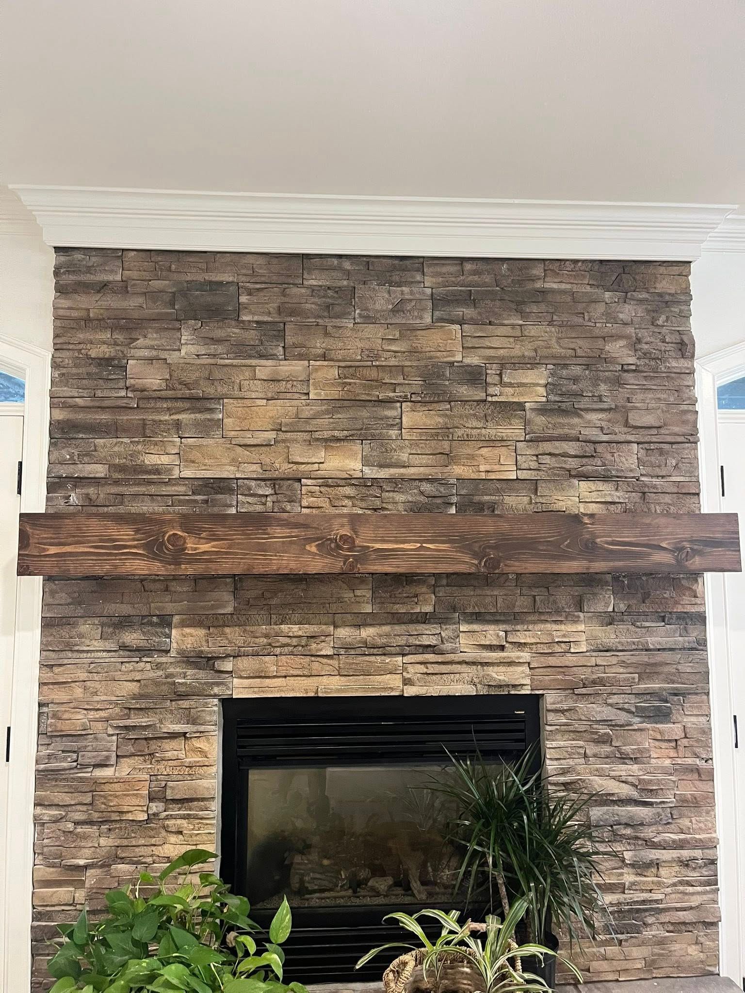 A stone fireplace with a thick, rustic wooden mantelpiece and white crown molding at the top.