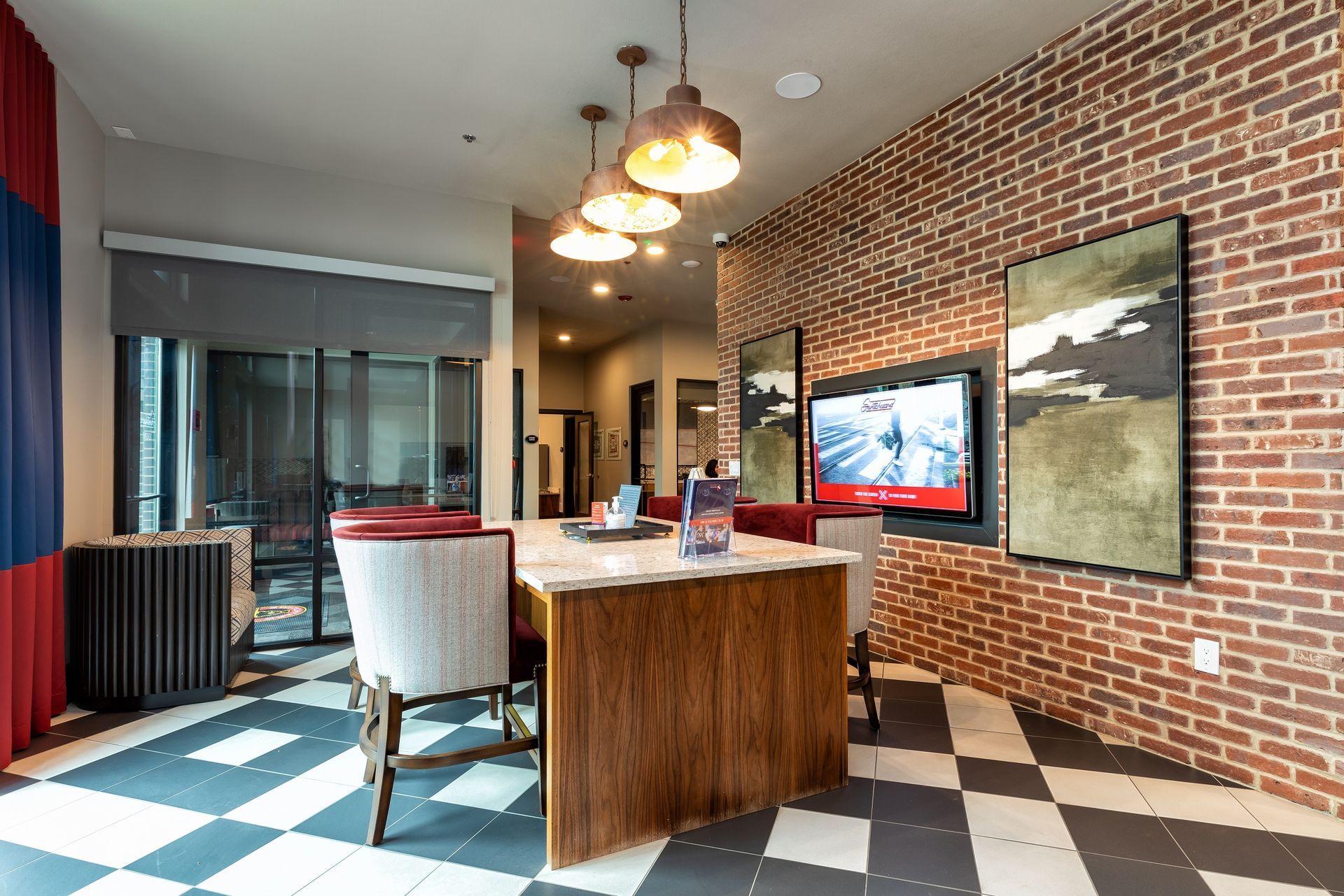Interior with checkered floor, brick wall, kitchen island, and artwork. Includes a TV and hanging lights.