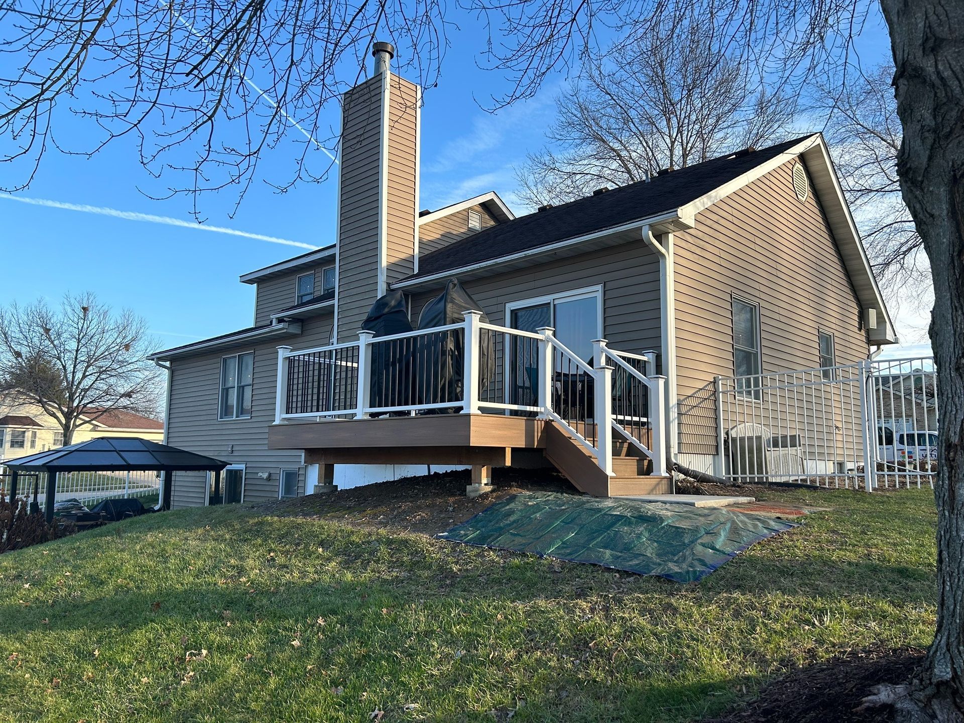 Beige house with deck, chimney, and yard on a sunny day.