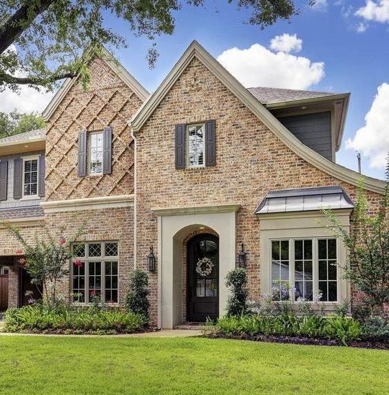 A large brick house with many windows and a wreath on the door