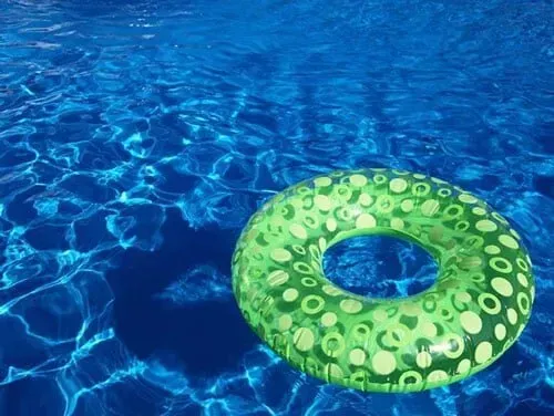 A green life preserver is floating in a swimming pool