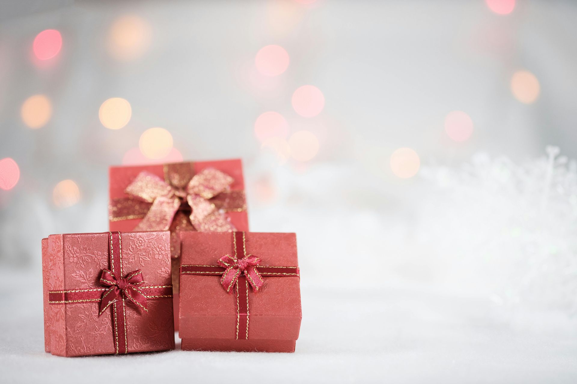 Three red christmas presents are stacked on top of each other on a white surface.