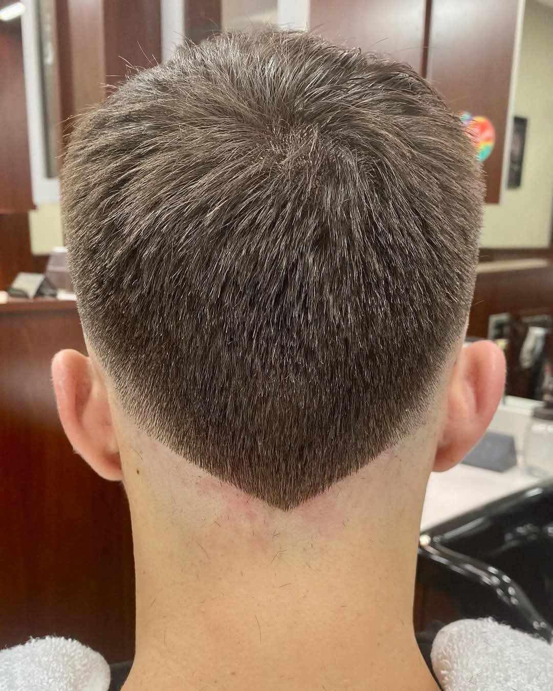 A back view of a person’s short haircut featuring a tapered fade ending in a V-shaped neckline.