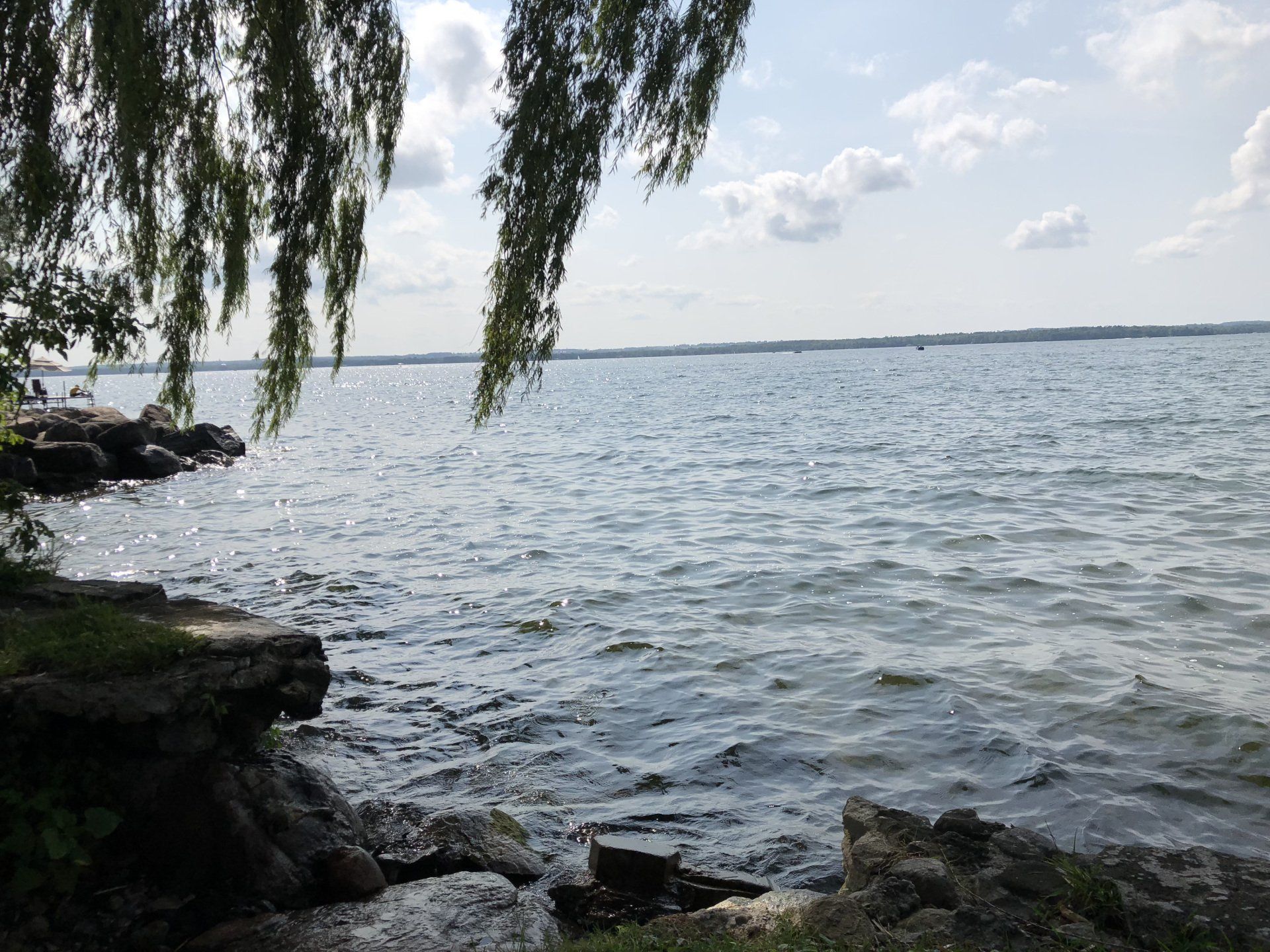 A large body of water is surrounded by rocks and trees on a sunny day.